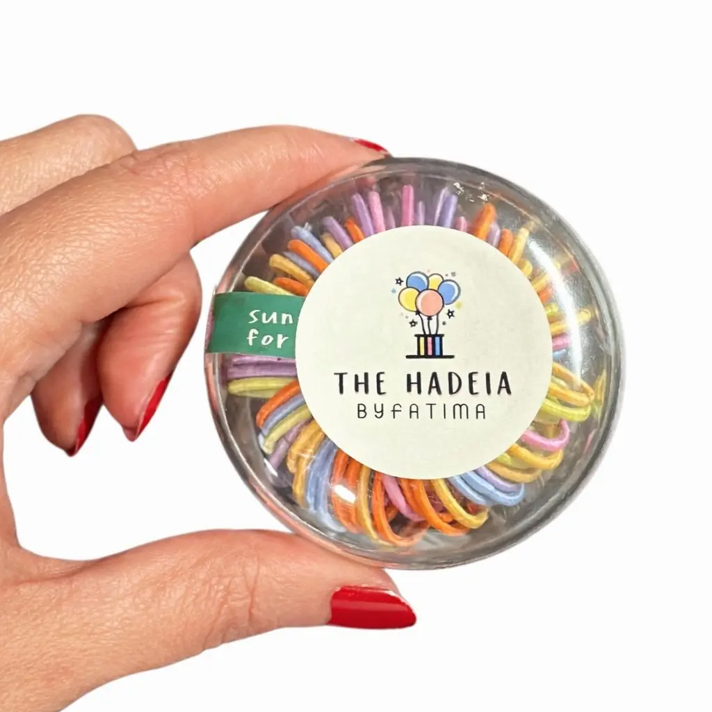 ربطات شعر ملونة في علبة دائرية شفافة — Multicolor hair ties in a round transparent box
